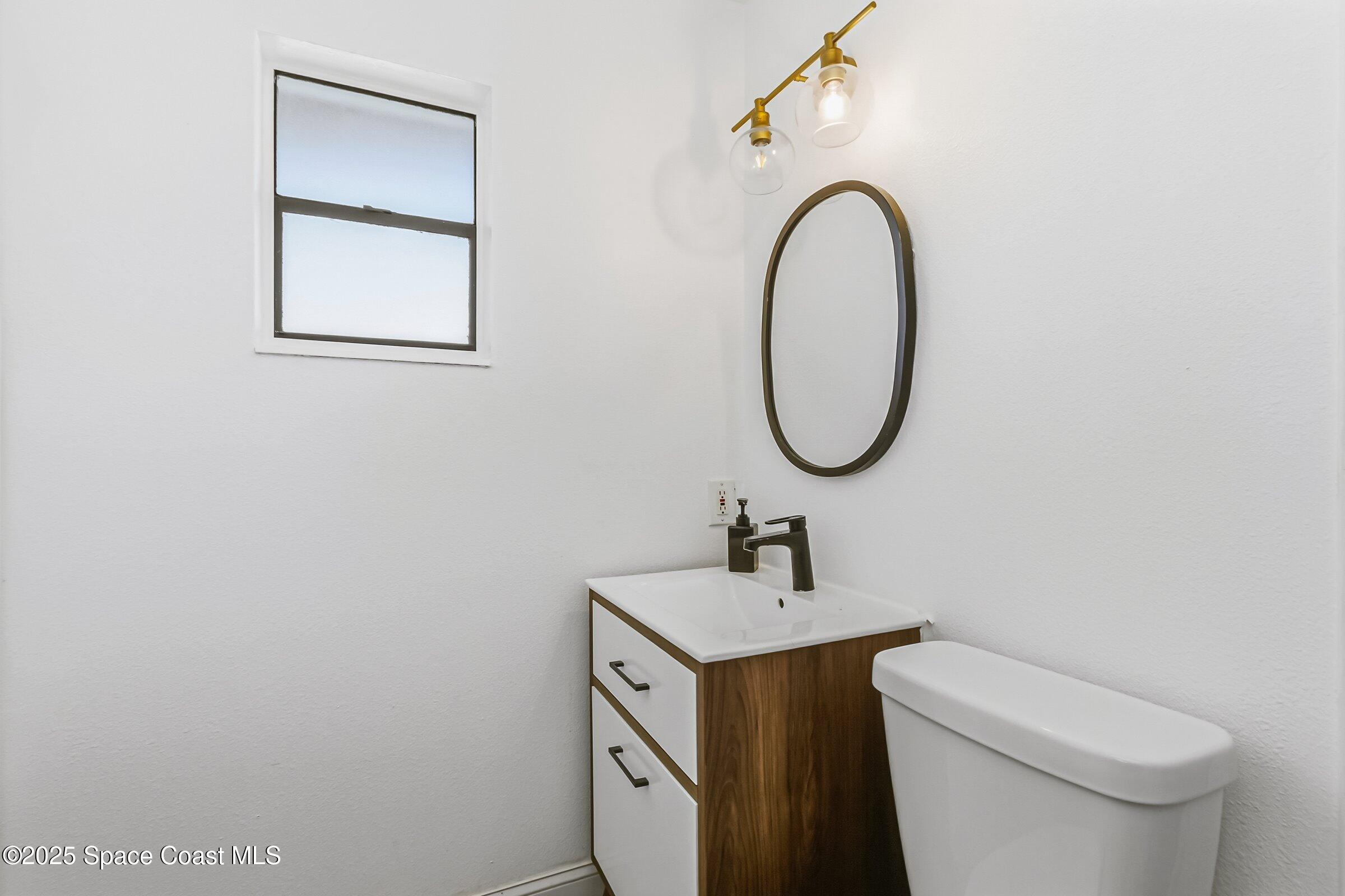 300 South Orlando Avenue, Unit 4 5 6 Cocoa Beach, FL 32931 - Photo 40 of 56 a bathroom with a toilet sink and mirror