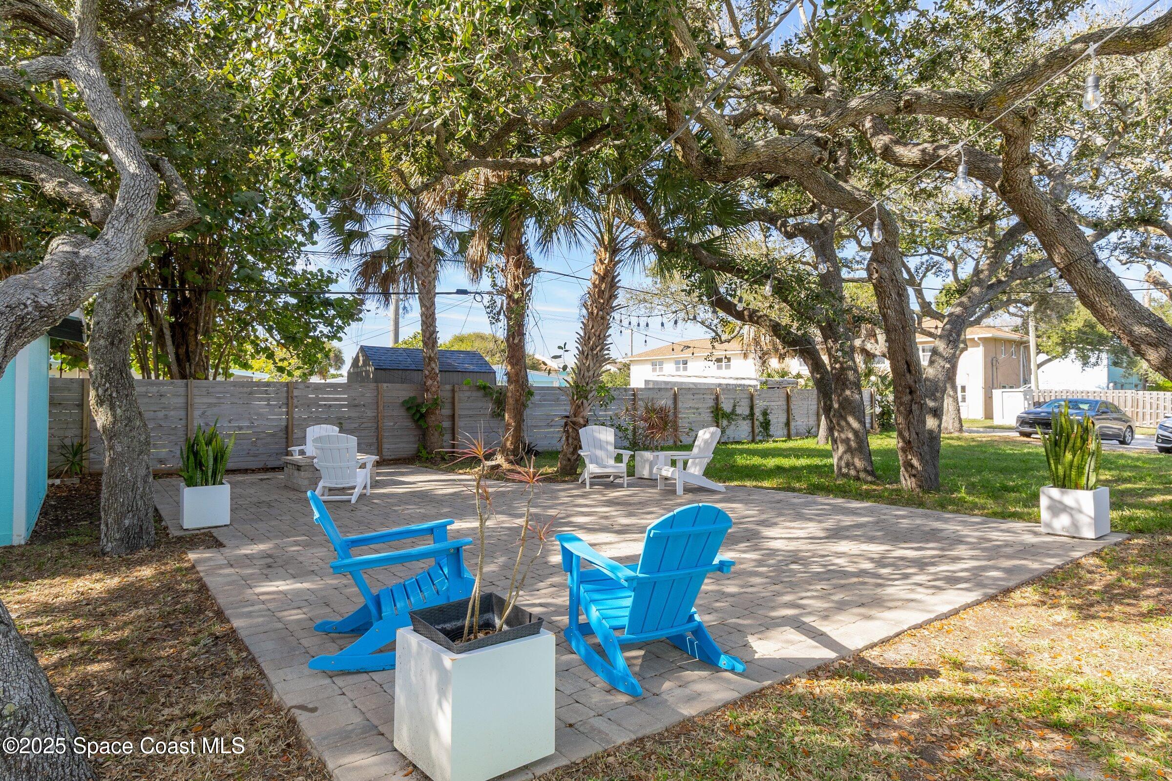 300 South Orlando Avenue, Unit 4 5 6 Cocoa Beach, FL 32931 - Photo 43 of 56 a view of a backyard with table and chairs potted plants and a large tree