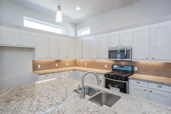 a kitchen with stainless steel appliances granite countertop a sink stove and cabinets