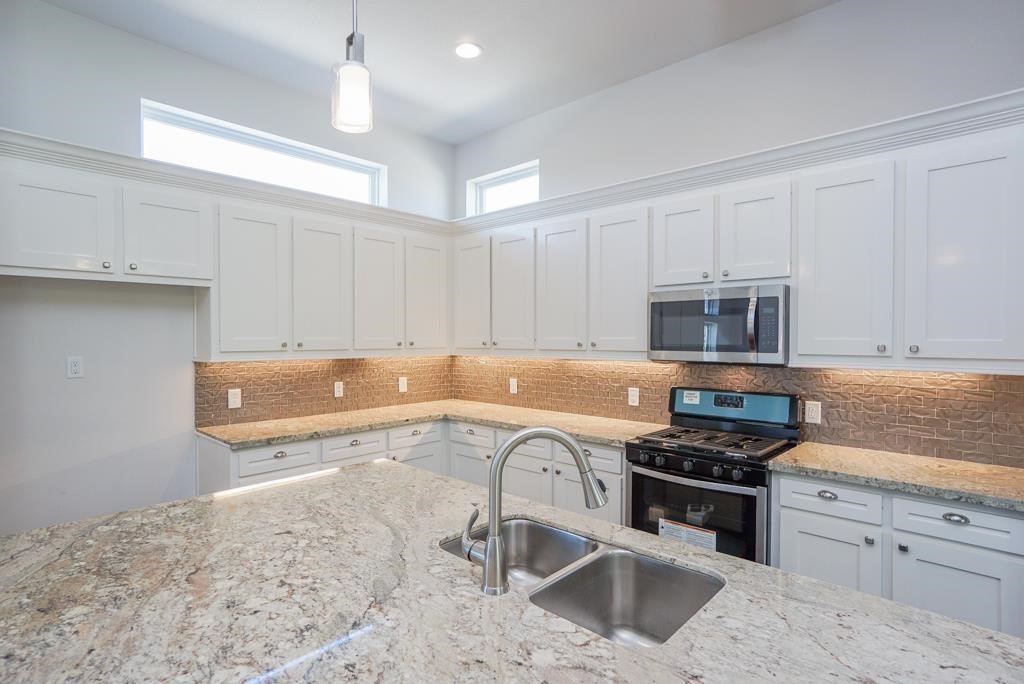 a kitchen with stainless steel appliances granite countertop a sink stove and cabinets