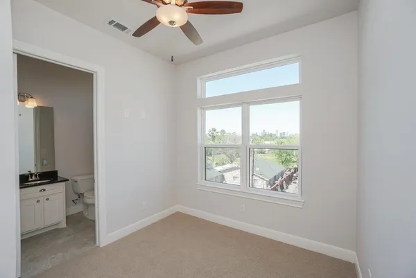 an empty room with a window and a ceiling fan