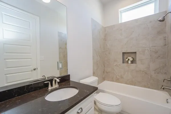 a bathroom with a granite countertop sink toilet a mirror and bathtub