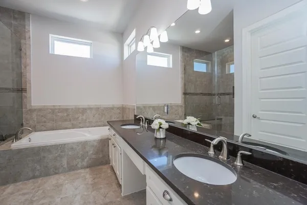 a bathroom with a granite countertop double vanity sink a mirror and a bathtub