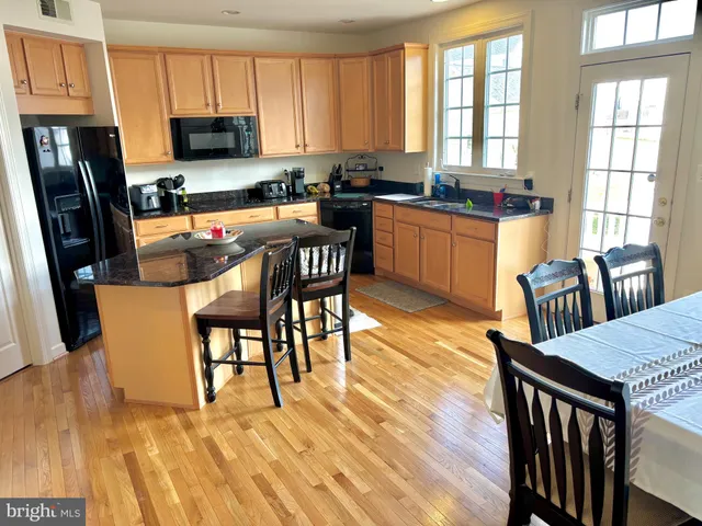 a kitchen with granite countertop a stove a sink a dining table and chairs