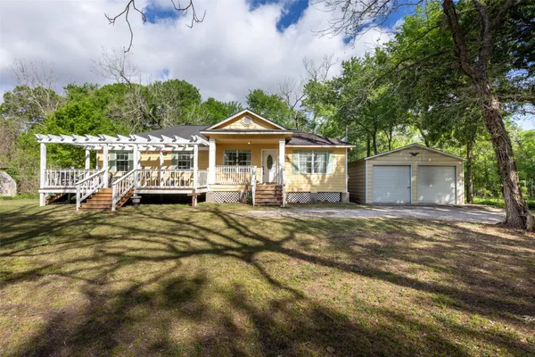 a front view of a house with a garden and trees
