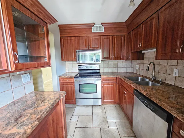 a kitchen with stainless steel appliances granite countertop a stove a sink and a microwave