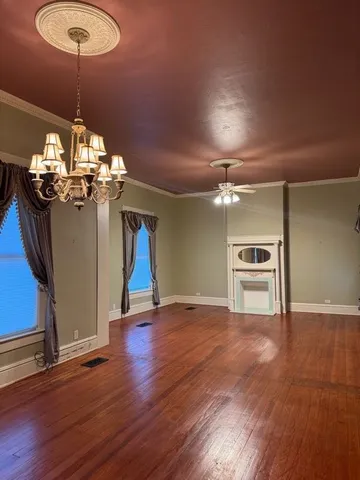 a view of a room with wooden floor chandelier and windows