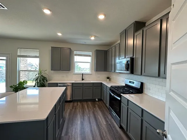 a kitchen with stainless steel appliances granite countertop sink stove microwave and cabinets
