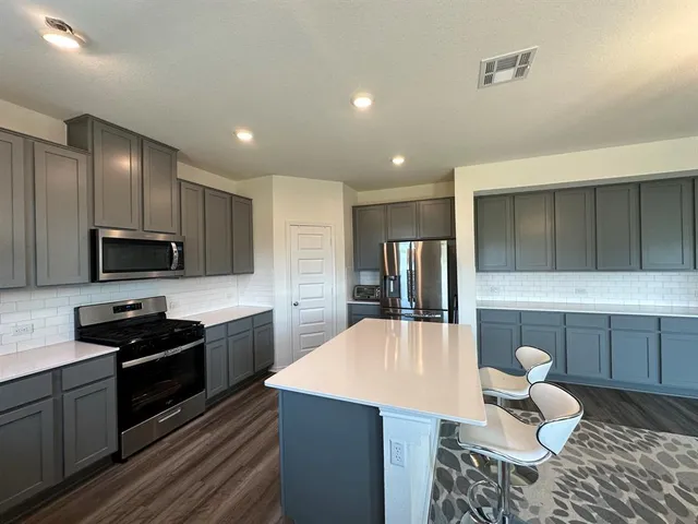 a kitchen with stainless steel appliances a stove a sink a microwave a refrigerator and cabinets