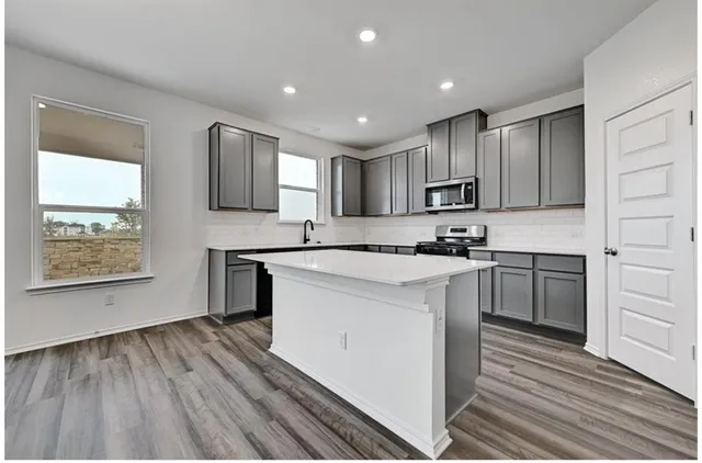 a kitchen with kitchen island granite countertop a sink cabinets and stainless steel appliances