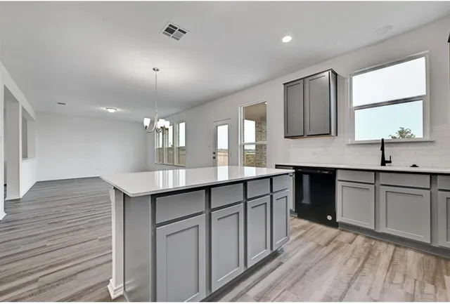 a kitchen with granite countertop a sink cabinets and wooden floor