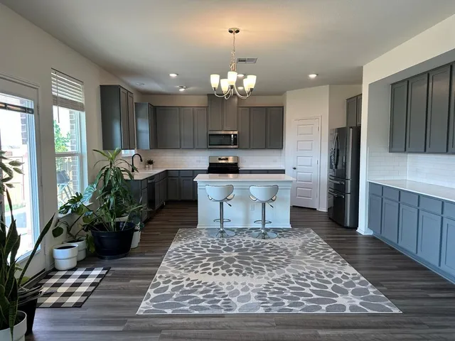 a kitchen with kitchen island granite countertop a sink refrigerator and cabinets