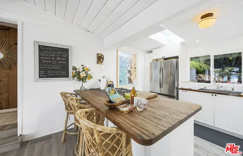 a view of a patio with couches and table and chairs under an umbrella with a small yard