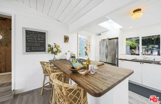 a view of a patio with couches and table and chairs under an umbrella with a small yard