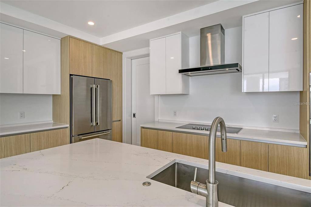 301 Quay Commons, Unit 1011 Sarasota, FL 34236 - Photo 20 of 75 a kitchen with a refrigerator and white cabinets