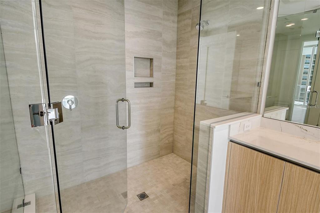 301 Quay Commons, Unit 1011 Sarasota, FL 34236 - Photo 25 of 75 a bathroom with a granite countertop sink a mirror and shower