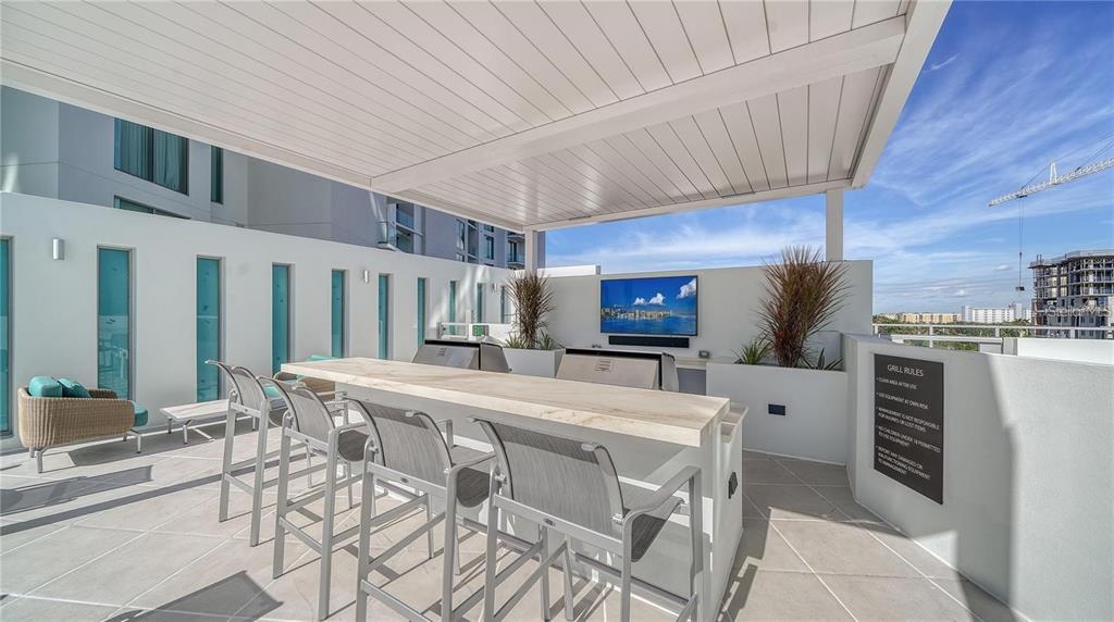 301 Quay Commons, Unit 1011 Sarasota, FL 34236 - Photo 68 of 75 a kitchen with stainless steel appliances kitchen island granite countertop a table chairs and a refrigerator