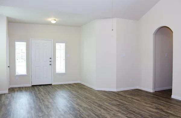 an empty room with wooden floor and window