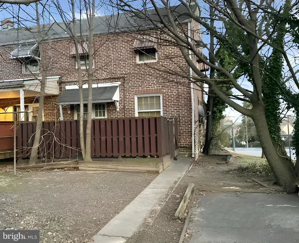 a view of a house with a wooden fence and a large tree