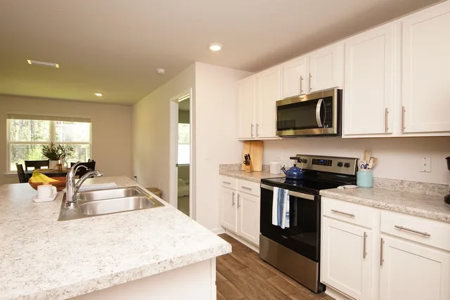 a view of a kitchen with kitchen island a sink wooden floor and stainless steel appliances