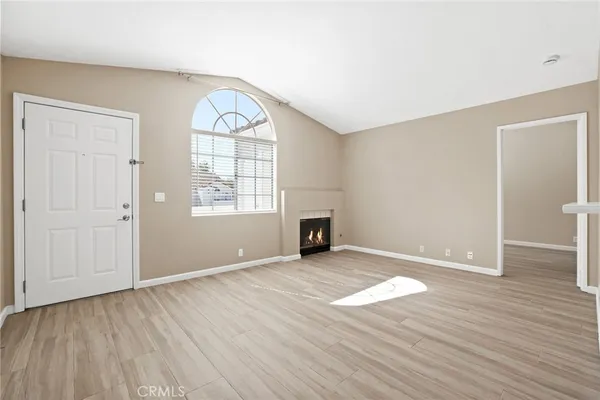 an empty room with wooden floor cabinet and windows