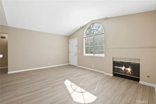 an empty room with wooden floor a fireplace and windows