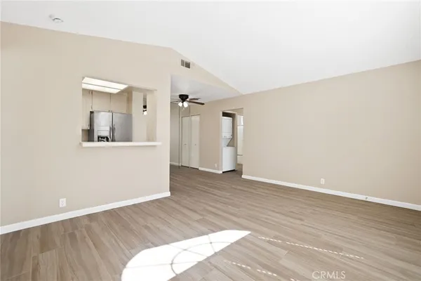 a view of an empty room with wooden floor and a mirror