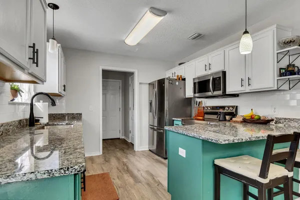 a kitchen with stainless steel appliances granite countertop a sink refrigerator and microwave