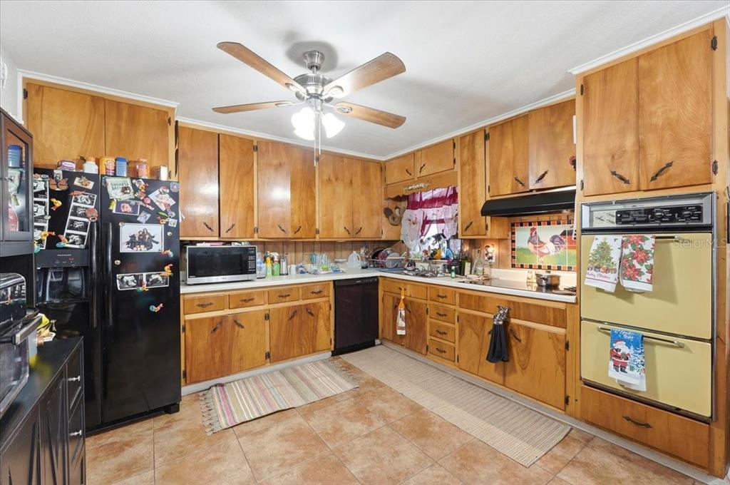 54 Gardner Avenue Lake Wales, FL 33898 - Photo 6 of 25 a kitchen with stainless steel appliances granite countertop a refrigerator a sink dishwasher a stove and a dining table with wooden floor
