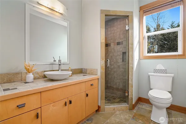 a bathroom with a granite countertop toilet a sink and a mirror