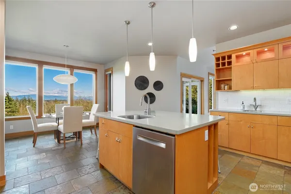 a dining hall with stainless steel appliances granite countertop a sink a counter space and a view of living room