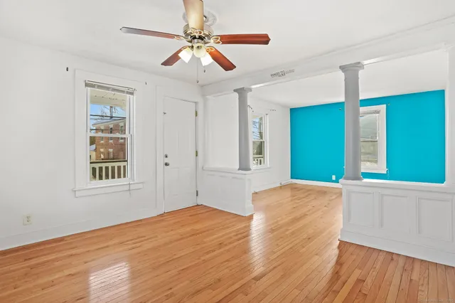 a view of an empty room with window and wooden floor