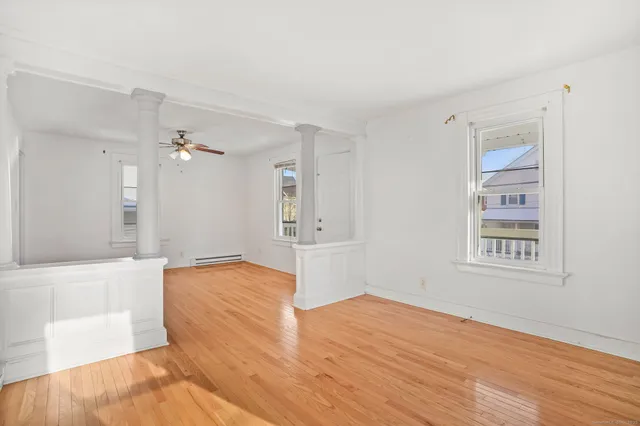 a view of empty room with wooden floor and fan