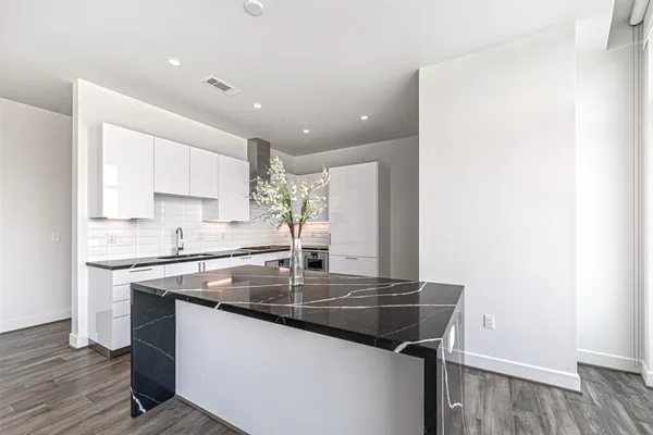 a kitchen with granite countertop a sink cabinets and wooden floor