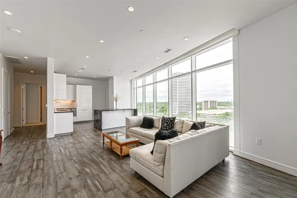 a living room with furniture floor to ceiling window and wooden floor