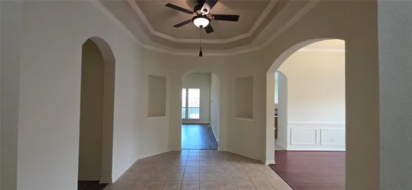 an empty room with wooden floor chandelier fan and windows