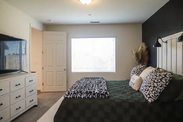 a bedroom with a bed and a flat tv screen on the dresser