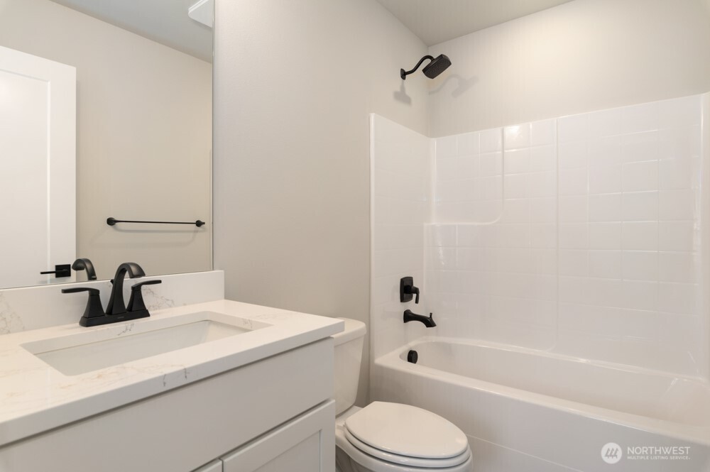 12814 66th Avenue South Seattle, WA 98178 - Photo 26 of 28 a bathroom with a sink a toilet a mirror a bathtub and shower
