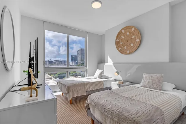 a bedroom with two beds and a lamp with the large mirror