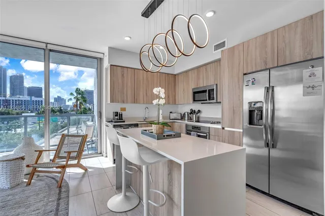 a kitchen with stainless steel appliances granite countertop a sink a stove a refrigerator cabinets and chairs