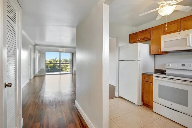 a view of a kitchen with a stove a refrigerator a ceiling fan and wooden floor