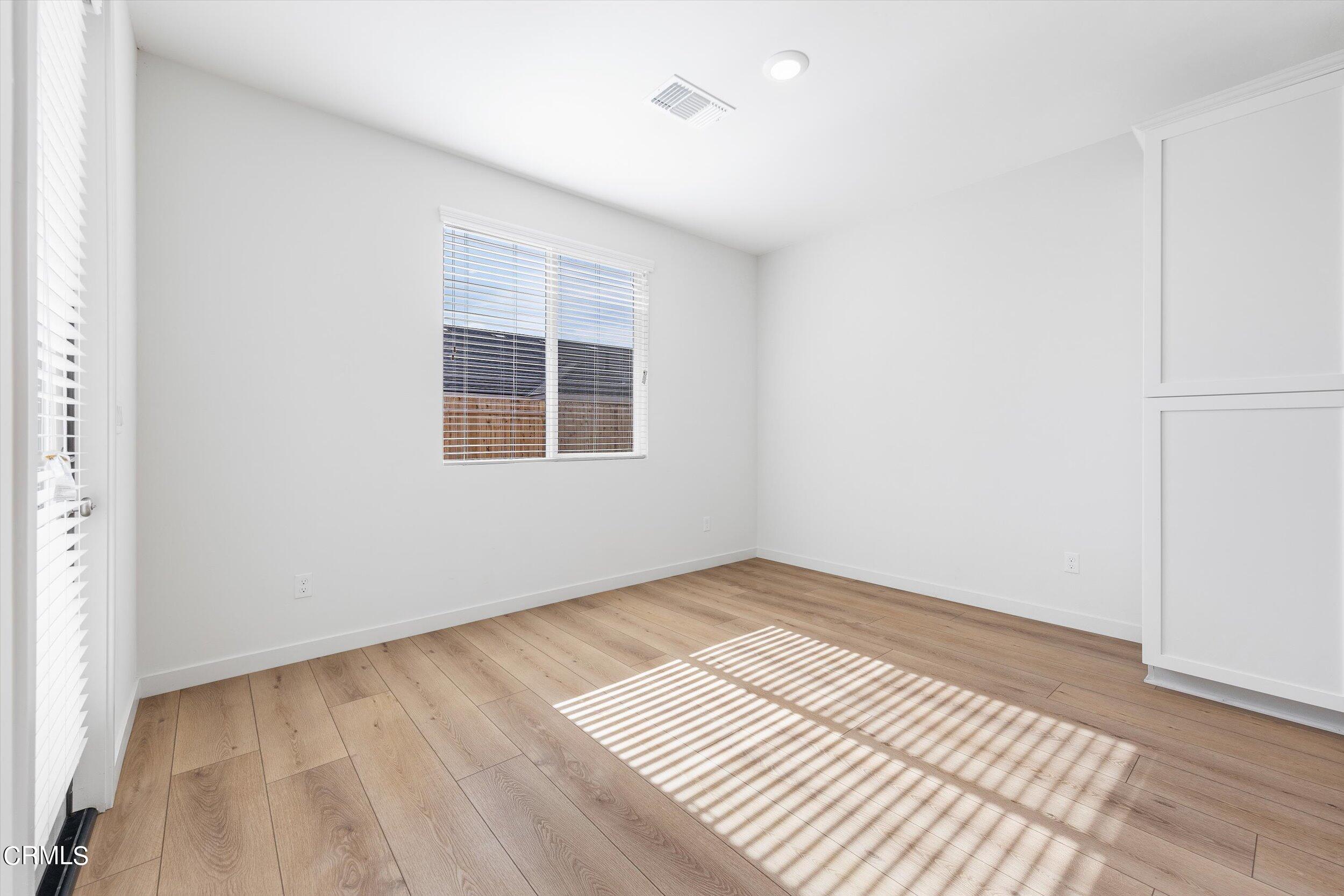 7405 Emerald Green Avenue Bakersfield, CA 93313 - Photo 13 of 39 an empty room with wooden floor and windows