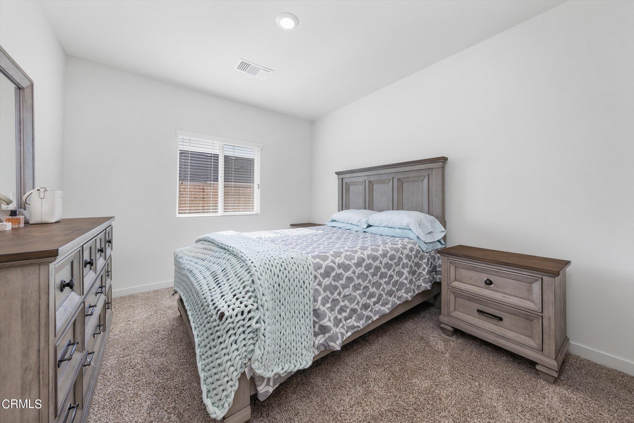 7405 Emerald Green Avenue Bakersfield, CA 93313 - Photo 25 of 39 a bedroom with a bed and a dresser next to a window