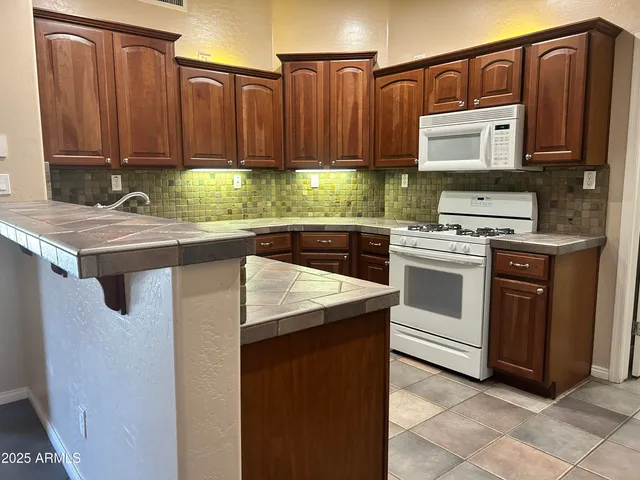 a kitchen with kitchen island granite countertop wooden cabinets and white appliances