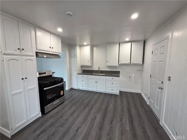 a kitchen with a sink a wooden floor and stainless steel appliances