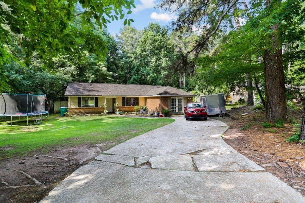 a front view of a house with a garden and trees