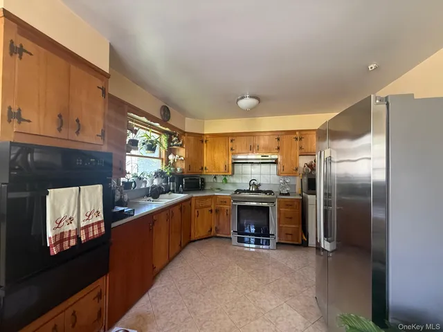 a kitchen with stainless steel appliances granite countertop a refrigerator a stove and a sink