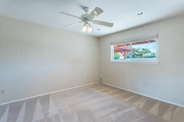 an empty room with windows and fan