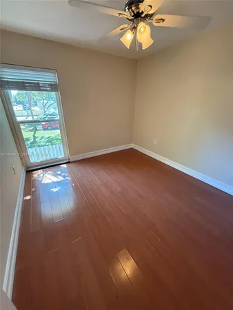 an empty room with wooden floor fan and windows
