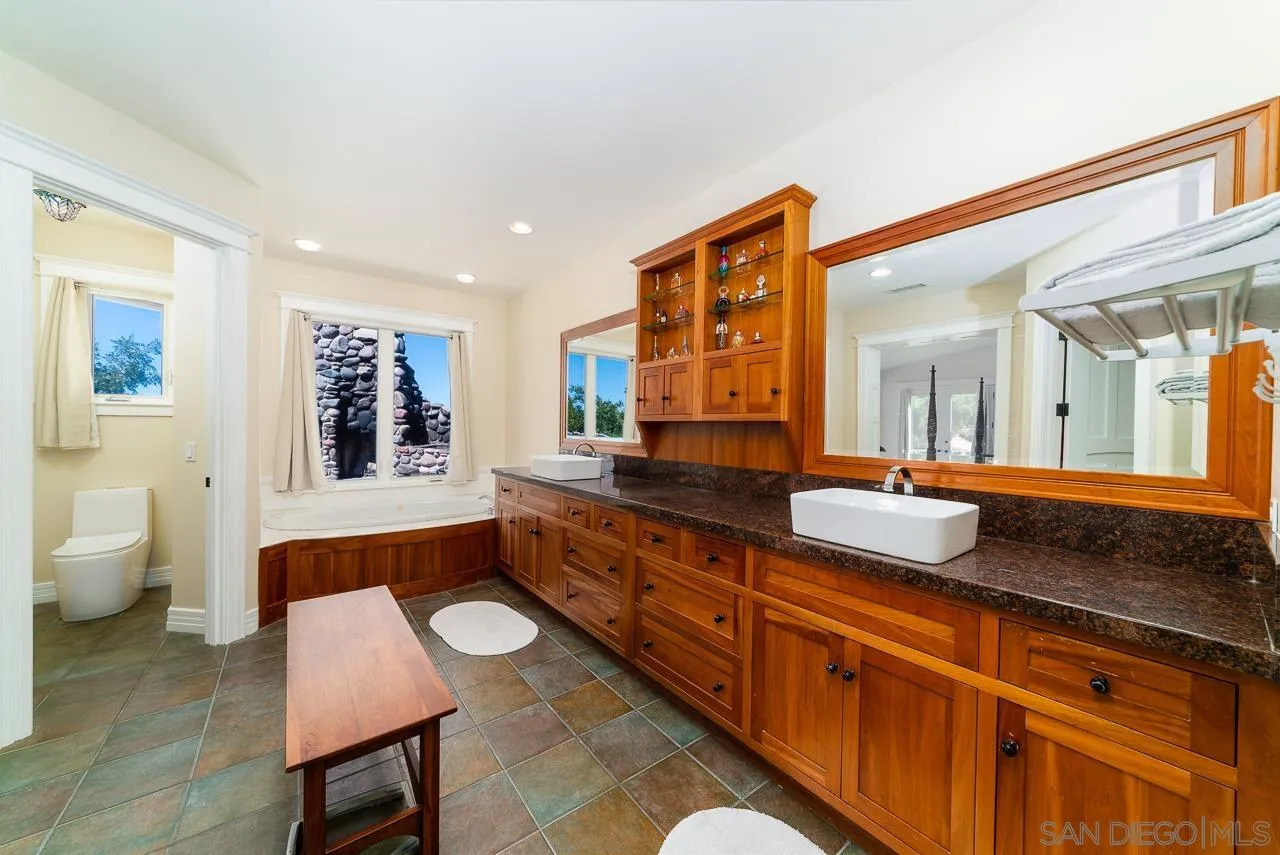 32070 Vía Vera Bonsall, CA 92003 - Photo 22 of 51 a spacious bathroom with a granite countertop sink and a large mirror